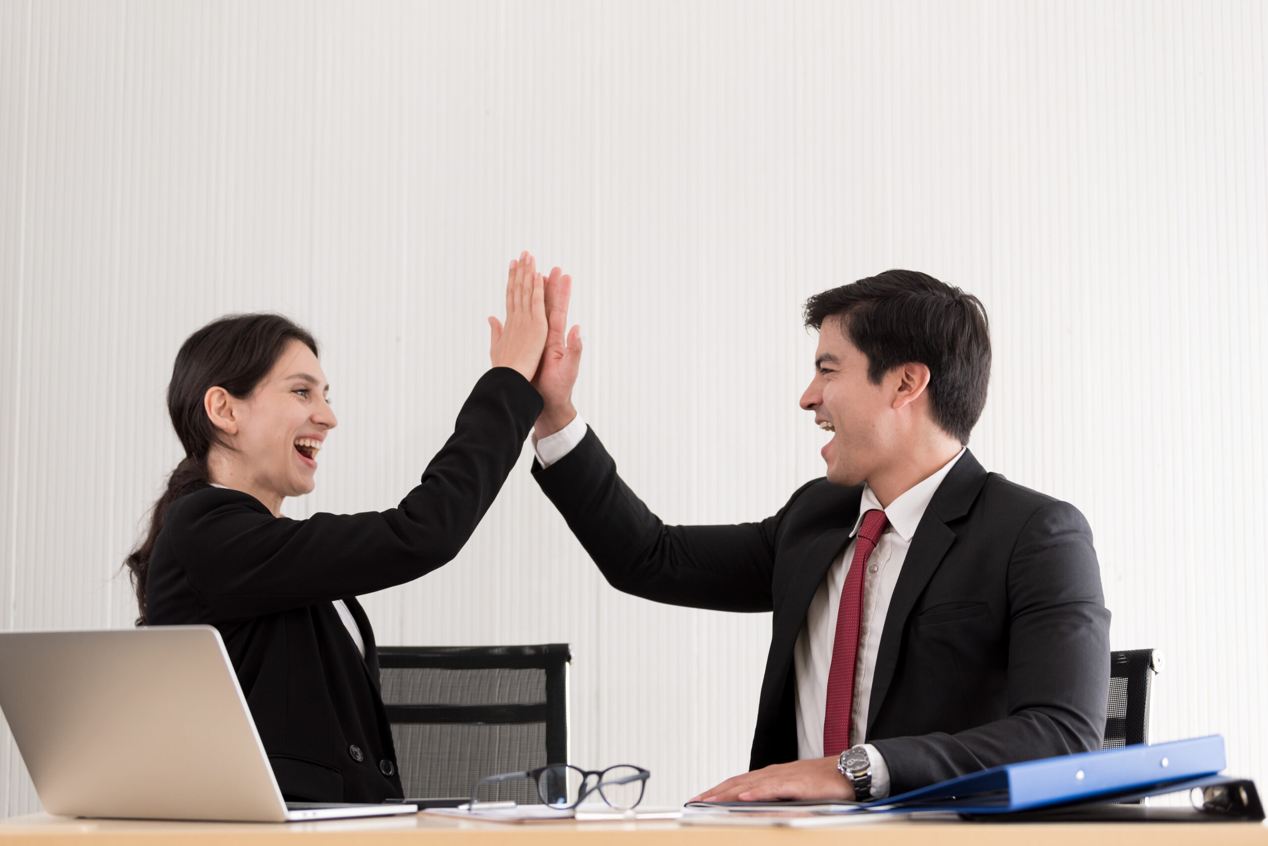 Two professionals high five each other because of job promotion.